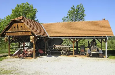 a wooden pavilion with a tractor and equipment in it at Tourist Farm Ferencovi in Cankova