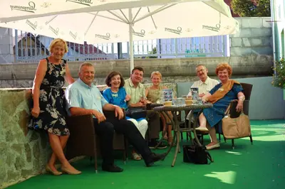 a group of people sitting at a table under an umbrella at Guesthouse Veles in Slovenska Bistrica