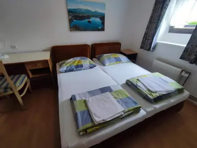 a small bedroom with a bed and a desk and a window at Guesthouse Veles in Slovenska Bistrica