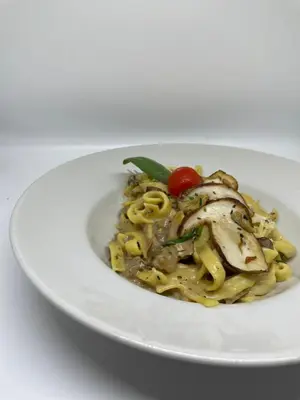a white plate of pasta with chicken and vegetables at Guesthouse Jurcek in Zreče