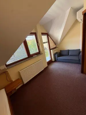 an attic room with a blue couch and windows at Guesthouse Jurcek in Zreče