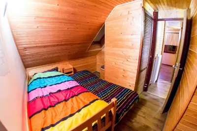 a small bedroom with a bed in a wooden room at Rogla Chalet Urska in Resnik