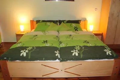 a bed with green sheets and a clock on it at Apartments Peternelj in Cerkno