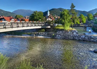 a bridge over a river with a town in the background at Farm Stay Loger in Ljubno