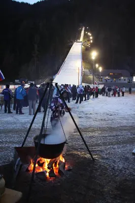 a pot of food over a fire with a crowd of people at Farm Stay Loger in Ljubno