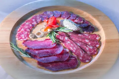 a plate of different types of meat on a table at Farm Stay Loger in Ljubno