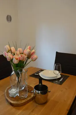 a wooden table with a vase with pink flowers in it at Apartment Kancler in Nova Gorica