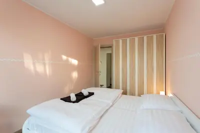 a bedroom with a bed with white sheets and a wooden cabinet at Apartment Kancler in Nova Gorica