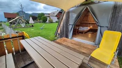 a view of a tent with a bench and a table at Garden ECO houses Čebelica in Bohinj