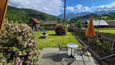 a patio with a table and chairs and an umbrella at Garden ECO houses Čebelica in Bohinj