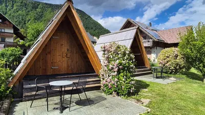 a house with a triangular roof with a table and chairs at Garden ECO houses Čebelica in Bohinj