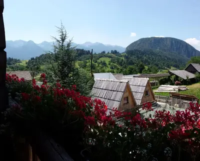 a view of a village with flowers and mountains at Garden ECO houses Čebelica in Bohinj