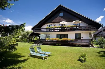 two chairs sitting on a lawn in front of a house at Lake Bled Apartment Zerovec in Bled