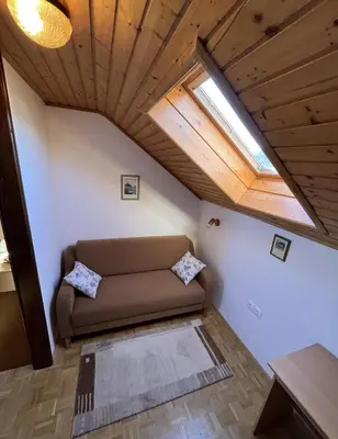 a couch in the corner of a room with a window at Lake Bled Apartment Zerovec in Bled