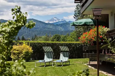 two chairs and an umbrella in a yard with mountains at Lake Bled Apartment Zerovec in Bled