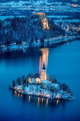 an island in the middle of a lake at night at Lake Bled Apartment Zerovec in Bled