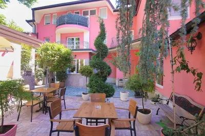 a patio with tables and chairs in front of a pink building at Boutique Hotel Asteria in Ljubljana