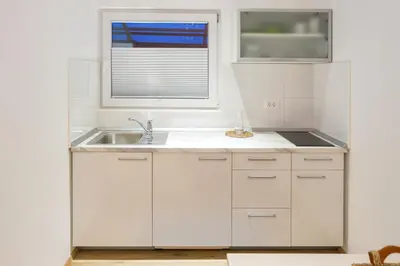 a white kitchen with a sink and a window at Apartments SHISHKA in Ljubljana