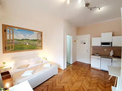 a living room with a white couch and a kitchen at B&B Vila Teslova in Ljubljana