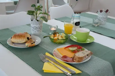 a table with two plates of breakfast foods and a cup of orange juice at B&B Vila Teslova in Ljubljana