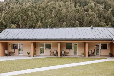 a house with a metal roof with a mountain in the background at Gostišče Krivograd in Prevalje