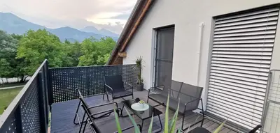 a balcony with chairs and a table with mountains in the background at 7th Mill apartments in Kranj