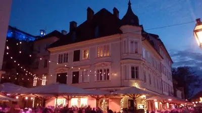 a large building with umbrellas in front of it at night at 3 Bridges App in Ljubljana