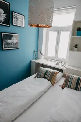two beds in a room with blue walls and a chandelier at Apartments Miki's in Bled