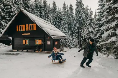 a man pulling a woman on a sled in front of a cabin at Chalet Trzinka - Triglav National Park in Goreljek