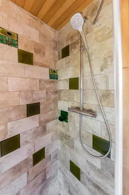 a shower in a bathroom with a stone wall at Chalet Trzinka - Triglav National Park in Goreljek