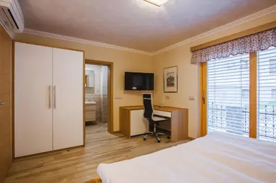 a bedroom with a bed and a desk and a television at Apartment Ledrar in Bled