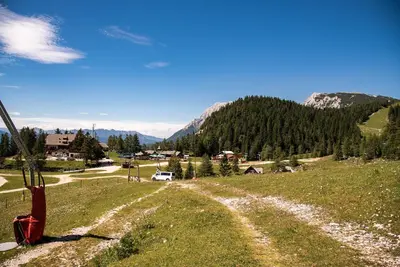 a dirt road in a field with mountains in the background at Apartments Zvoh, Krvavec, Ski-in, Ski-out in Cerklje na Gorenjskem