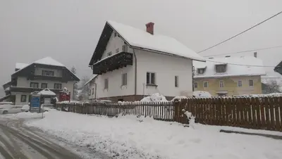 a house is covered in snow next to a fence at House Cilka in Kranjska Gora