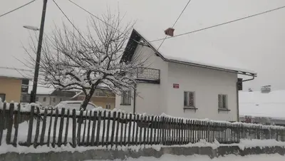 a fence covered in snow next to a white house at House Cilka in Kranjska Gora