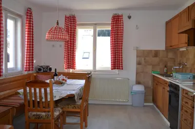 a kitchen with a table and chairs and red curtains at House Cilka in Kranjska Gora