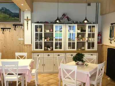 a kitchen with white cabinets and white tables and chairs at Penzion Valerija in Zgornje Jezersko