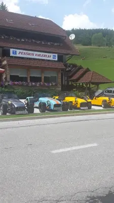 a row of race cars parked in front of a building at Penzion Valerija in Zgornje Jezersko