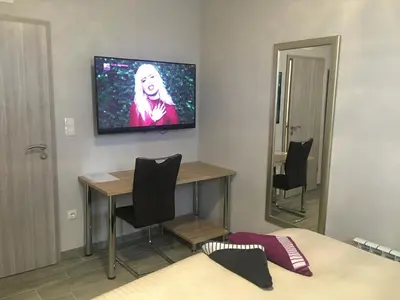 a room with a table and a television on the wall at Rooms & Apartments Banjac in Maribor