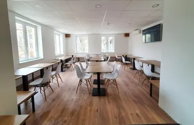 an empty classroom with tables and chairs and windows at Life Hostel Slovenia in Radovljica