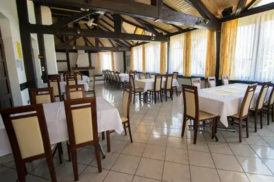 a dining room with white tables and chairs and windows at Župančičev hram in Dragatuš