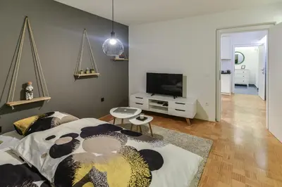 a living room with a bed and a television at Strict city apartments in Ljubljana