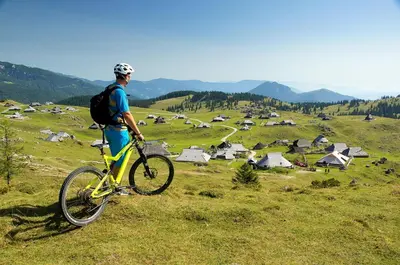 a man standing with a bike on a hill at Koča Ojstrica - Velika planina in Stahovica