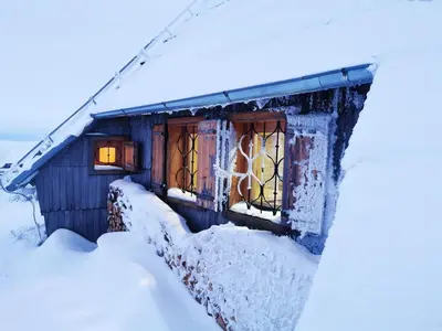 a house covered in snow with a window at Koča Ojstrica - Velika planina in Stahovica