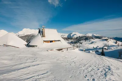 a snow covered house on top of a snow covered mountain at Koča Ojstrica - Velika planina in Stahovica