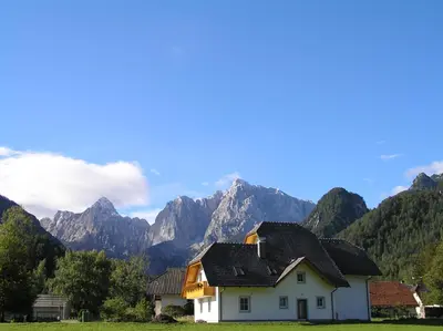 a white house with mountains in the background at Apartmaji Mlinar in Kranjska Gora