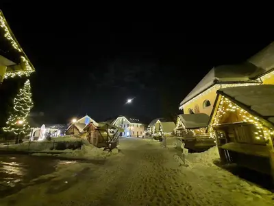a snow covered street at night with christmas lights at Apartmaji Mlinar in Kranjska Gora