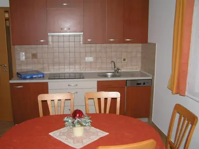 a kitchen with a table and chairs and a kitchen with a sink at Apartmaji Mlinar in Kranjska Gora