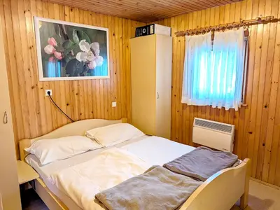 a bedroom with a bed in a wooden wall at Čebelarjeva hiška 1 - Terme Olimia - Podčetrtek in Podčetrtek