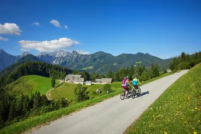 two people riding bikes down a road in the mountains at Prenočišča Mraz in Velenje
