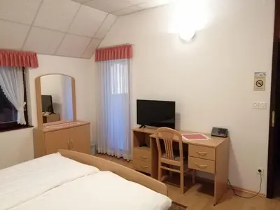 a bedroom with a bed and a desk with a television at Prenočišča Mraz in Velenje